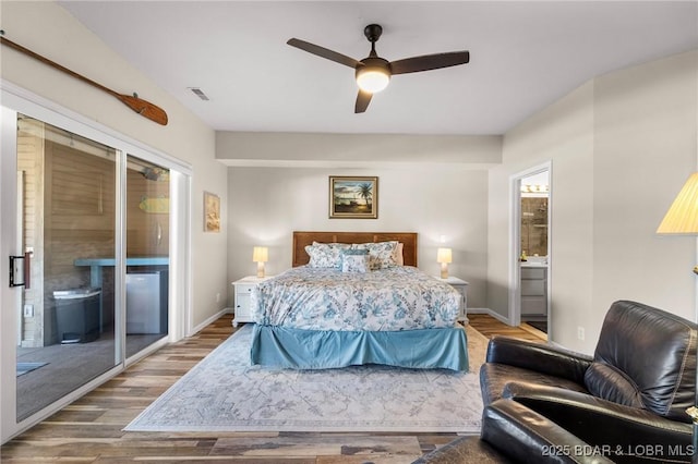 bedroom featuring visible vents, baseboards, wood finished floors, ensuite bath, and access to outside