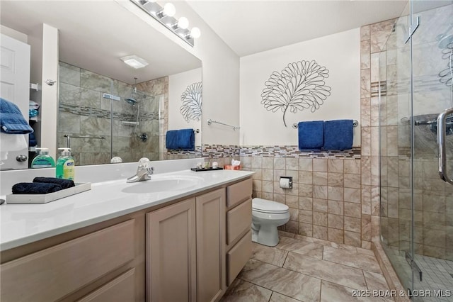 full bathroom featuring toilet, a stall shower, vanity, and tile walls