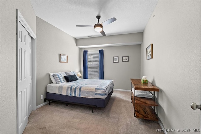 carpeted bedroom with ceiling fan, baseboards, a closet, and a textured ceiling