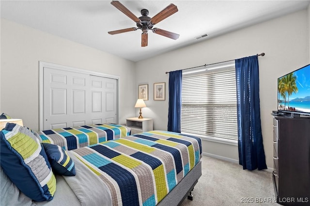 bedroom with visible vents, light carpet, a closet, baseboards, and ceiling fan