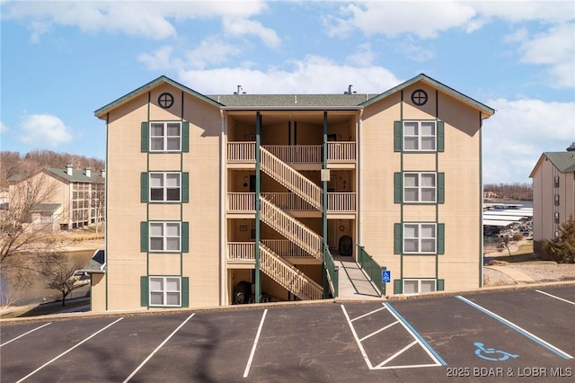 view of building exterior featuring stairway and uncovered parking