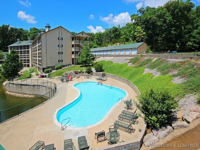 pool with a patio area and fence