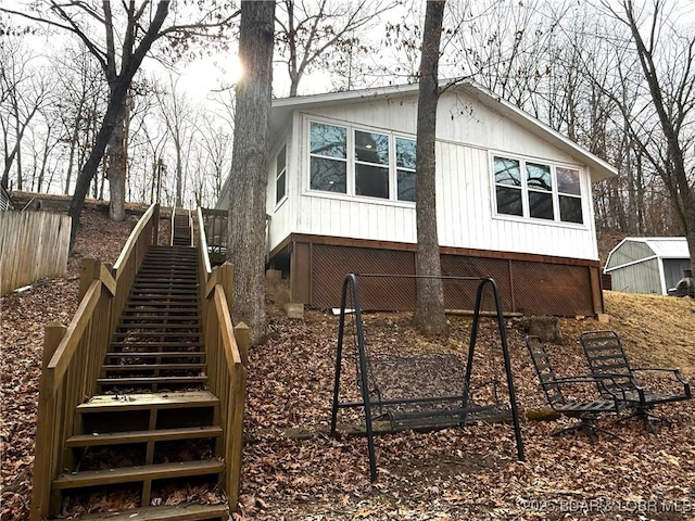 rear view of property with stairs and an outdoor structure