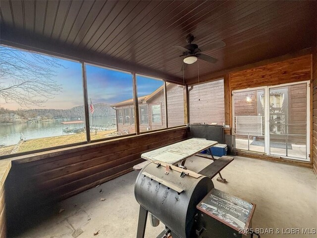 sunroom featuring a water view and a ceiling fan