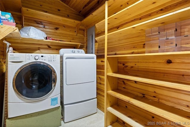 clothes washing area featuring laundry area, wood walls, and washing machine and clothes dryer