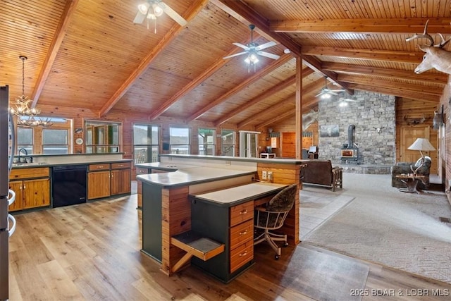 kitchen featuring a wood stove, vaulted ceiling with beams, a sink, black dishwasher, and open floor plan