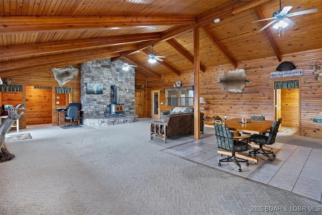 unfurnished bedroom with beam ceiling, a wood stove, carpet flooring, and wood walls