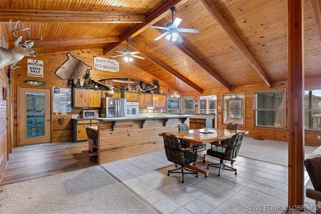 dining room featuring light tile patterned flooring, wood walls, light colored carpet, wood ceiling, and vaulted ceiling with beams