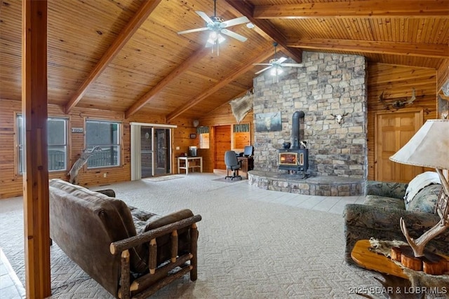 carpeted living area with lofted ceiling with beams, wooden ceiling, wood walls, and a wood stove