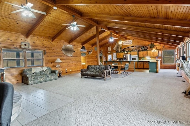 unfurnished living room with lofted ceiling with beams, wooden walls, a ceiling fan, and light colored carpet