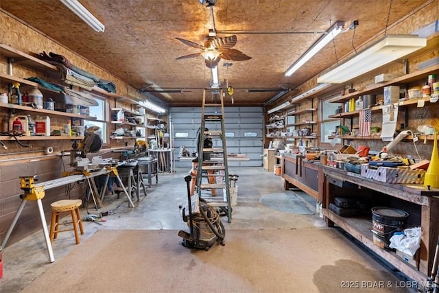 misc room featuring a workshop area, a garage, concrete flooring, and ceiling fan