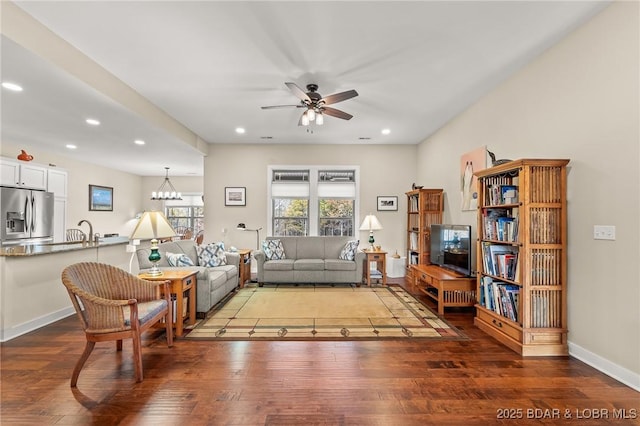 living room featuring recessed lighting, ceiling fan with notable chandelier, baseboards, and wood finished floors