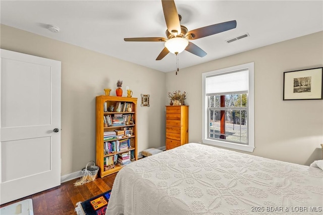 bedroom with hardwood / wood-style floors, baseboards, visible vents, and ceiling fan