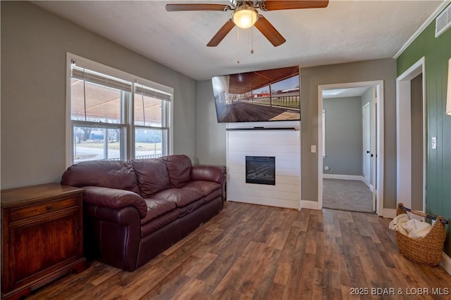 living area featuring visible vents, wood finished floors, a fireplace, baseboards, and ceiling fan