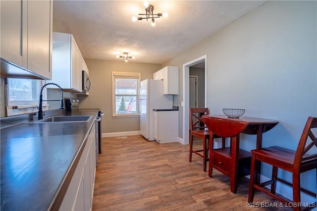 409 S Walnut St, Versailles, MO 65084 - kitchen featuring stainless steel countertops, stainless steel microwave, electric range oven, white cabinets, and freestanding refrigerator