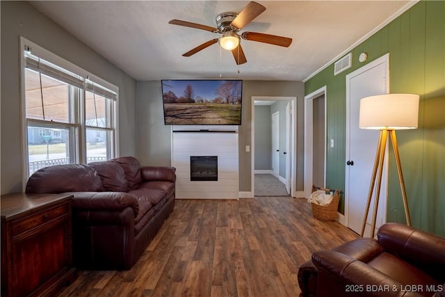 living area with visible vents, a ceiling fan, wood finished floors, and a fireplace