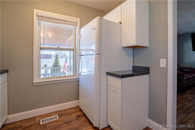 kitchen featuring wood finished floors, visible vents, baseboards, white cabinets, and dark countertops