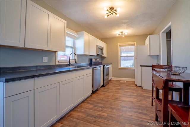 409 S Walnut St, Versailles, MO 65084 - kitchen with appliances with stainless steel finishes, a sink, dark countertops, wood finished floors, and plenty of natural light