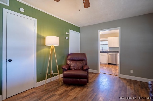 living area featuring visible vents, crown molding, ceiling fan, baseboards, and wood finished floors