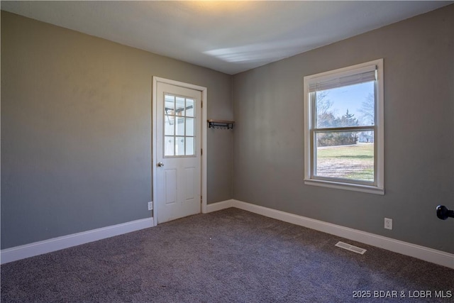 spare room featuring visible vents, a healthy amount of sunlight, baseboards, and carpet floors