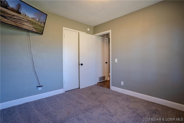 unfurnished bedroom featuring carpet, visible vents, and baseboards