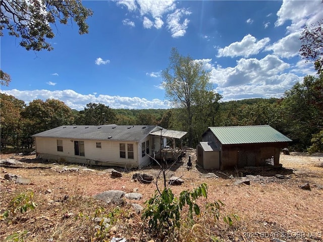 rear view of house with a wooded view and an outdoor structure