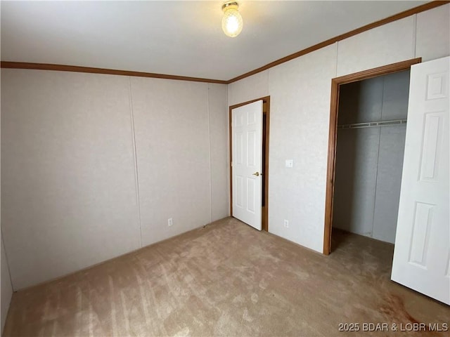 unfurnished bedroom featuring a closet, ornamental molding, and carpet flooring