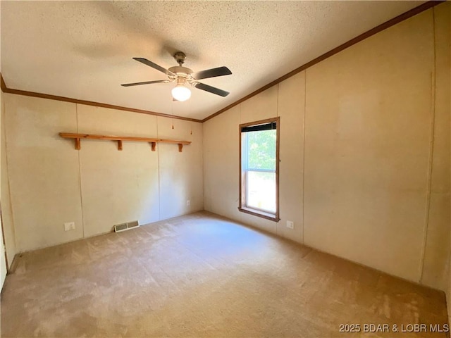 carpeted empty room with visible vents, ceiling fan, ornamental molding, vaulted ceiling, and a textured ceiling