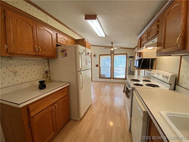 kitchen with wallpapered walls, light countertops, vaulted ceiling, brown cabinets, and white appliances