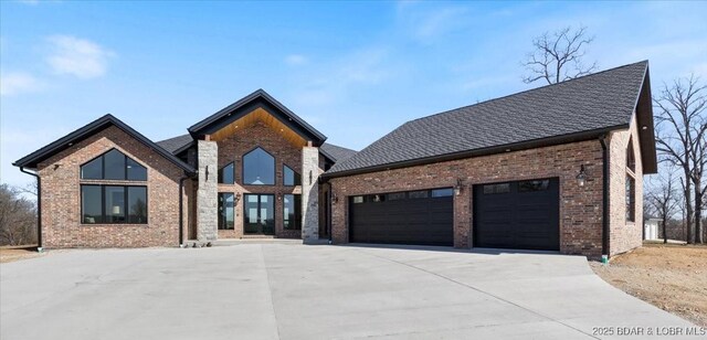 contemporary home featuring driveway, brick siding, a garage, and roof with shingles