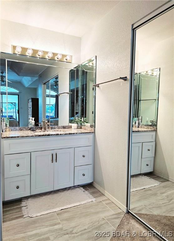 bathroom with wood finish floors, two vanities, a textured wall, and a sink