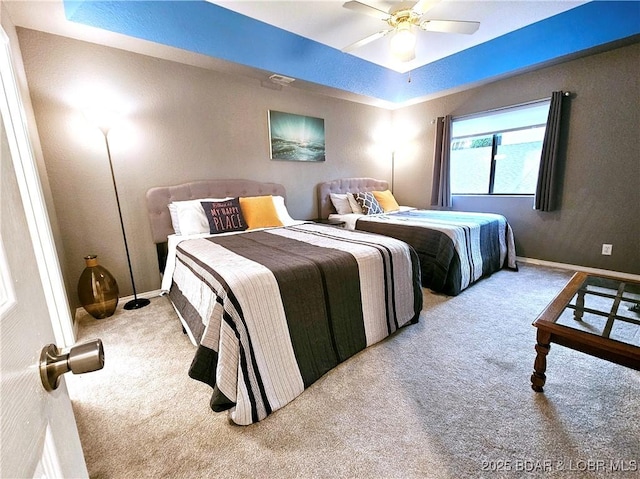 bedroom featuring baseboards, a raised ceiling, carpet floors, and a ceiling fan