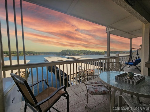 balcony at dusk featuring a water view