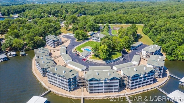 drone / aerial view with a wooded view and a water view