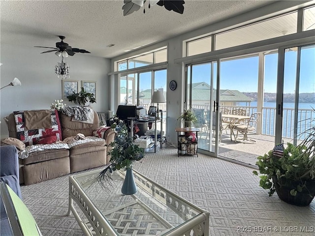 living room with a textured ceiling, a water view, carpet floors, and a ceiling fan