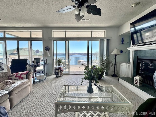 living area featuring a healthy amount of sunlight, visible vents, carpet floors, and a ceiling fan