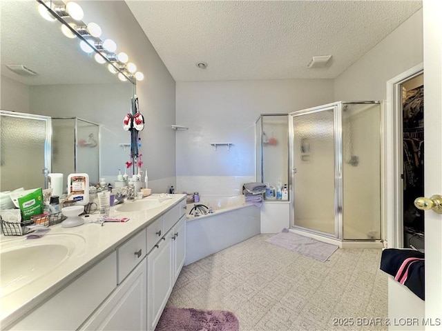 bathroom with tile patterned floors, a sink, a shower stall, a textured ceiling, and a bath