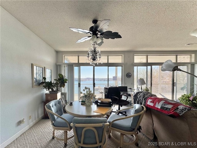 dining room with a water view, a textured ceiling, baseboards, carpet floors, and a textured wall