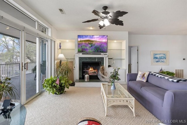 living area with ceiling fan, visible vents, and a high end fireplace