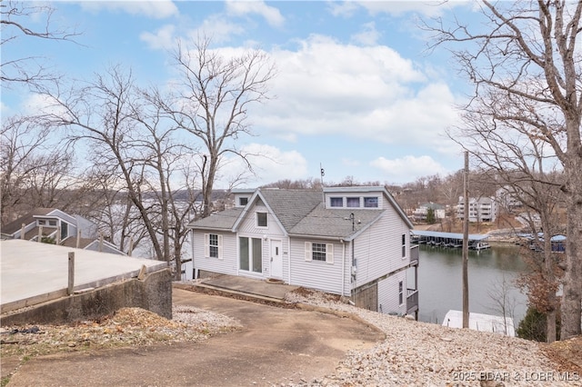 view of front of home featuring a water view, roof with shingles, and driveway