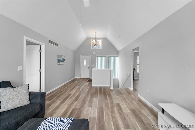 living area featuring light wood finished floors, vaulted ceiling, and baseboards