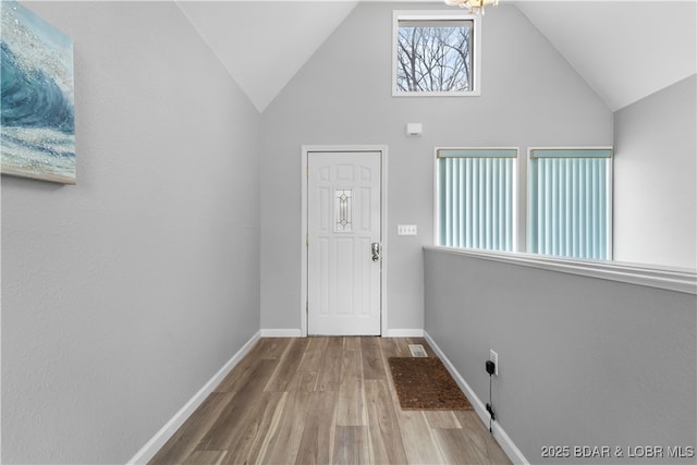 entryway featuring wood finished floors, baseboards, and high vaulted ceiling