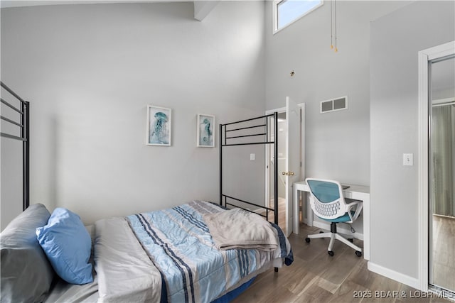 bedroom featuring wood finished floors and a high ceiling