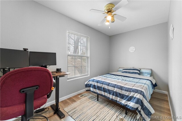 bedroom featuring wood finished floors, baseboards, a desk, and ceiling fan