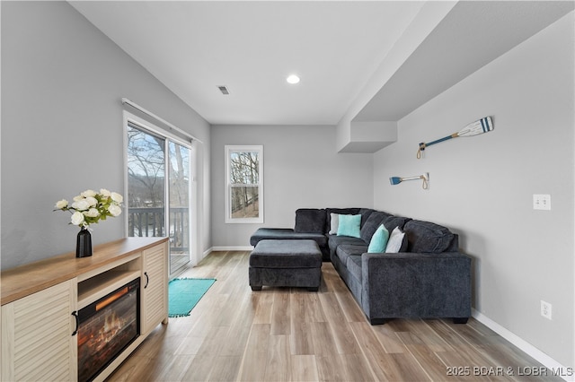 living room featuring light wood-type flooring, baseboards, and recessed lighting