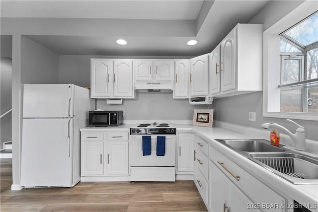 kitchen with white appliances, under cabinet range hood, a sink, recessed lighting, and white cabinetry