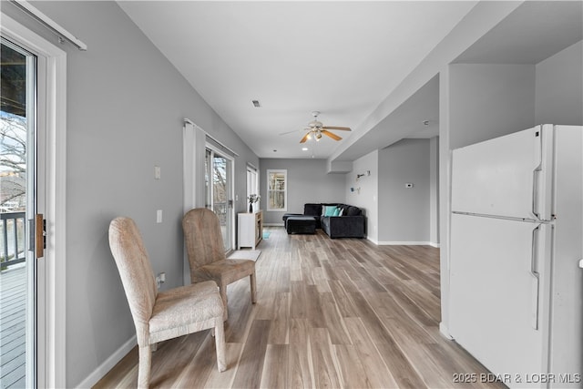 sitting room featuring light wood finished floors, a ceiling fan, and baseboards