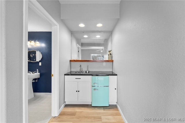 indoor wet bar featuring light wood-style flooring, baseboards, and recessed lighting