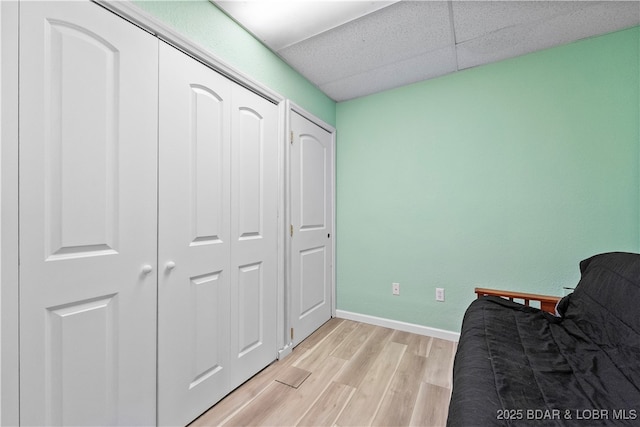 sitting room with light wood-style flooring, baseboards, and a drop ceiling