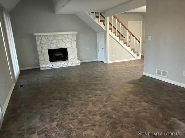 unfurnished living room featuring stairs, baseboards, visible vents, and a fireplace